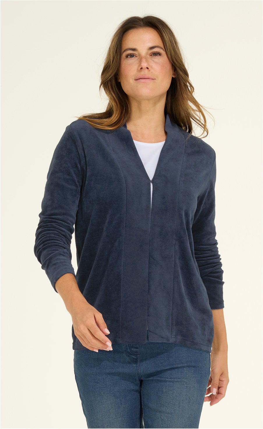 Frau trägt dunkelblaue Viskose-Mix-Jacke mit langen Ärmeln und offenem Kragen, kombiniert mit weißem Shirt und blauen Jeans, vor hellem Hintergrund
