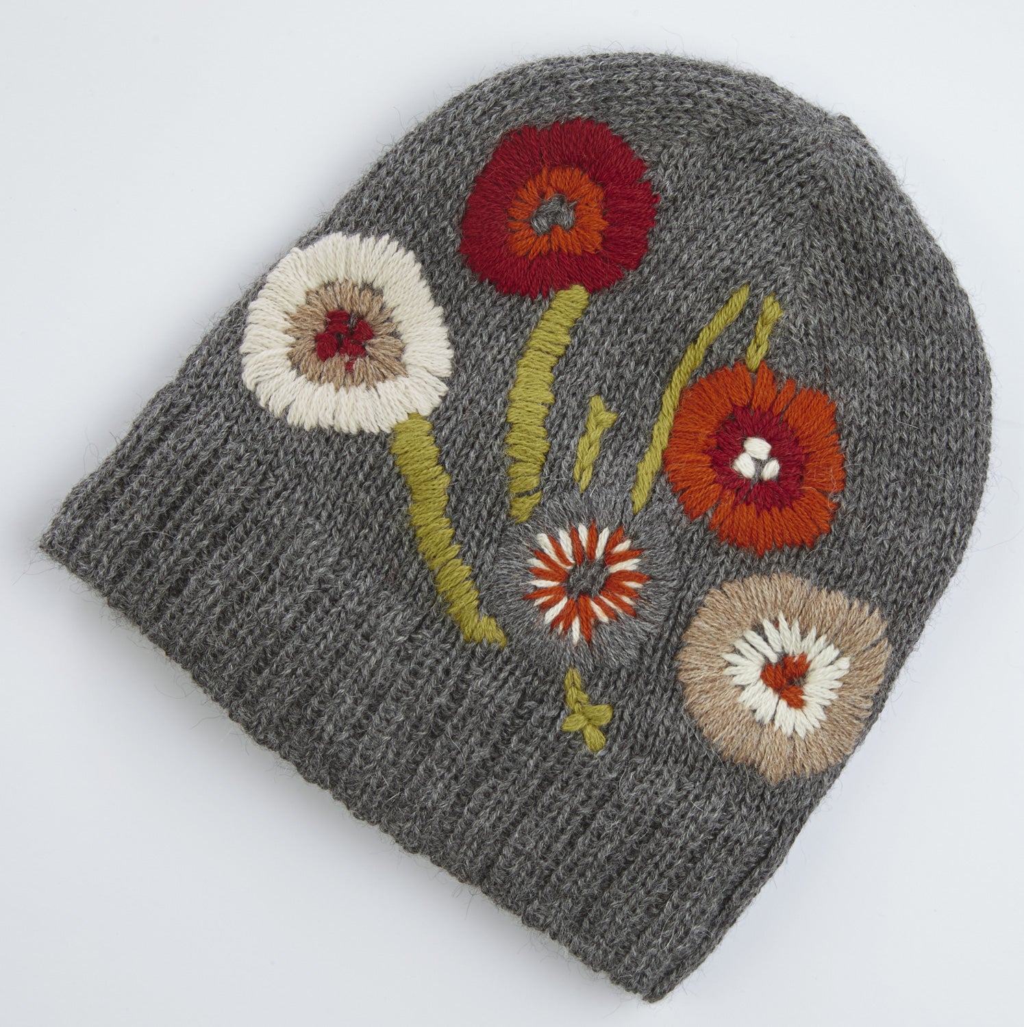 Grau gestrickte Alpaka-Mütze mit bunter, gestickter Blumenverzierung in Rot, Orange, Weiß und Beige, grüne Stängel und Blätter, grobe Strickstruktur, warme Winterkopfbedeckung