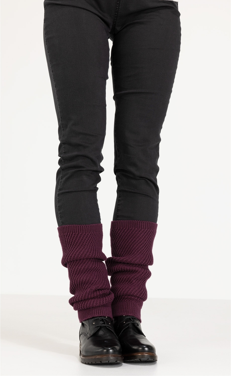 Beine in schwarzer Hose, schwarze Schnürschuhe, dunkelrote gestrickte Baumwoll-Mix-Stulpen, die lässig über den Schuhen getragen werden