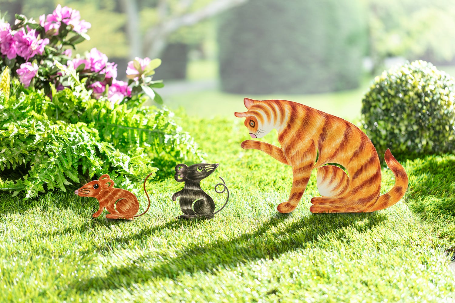 Metall-Gartenstecker Set bestehend aus einer orangetigergestreiften Katze und zwei Mäusen in Braun und Schwarz auf grünem Rasen mit Blüten und grünen Büschen im Hintergrund