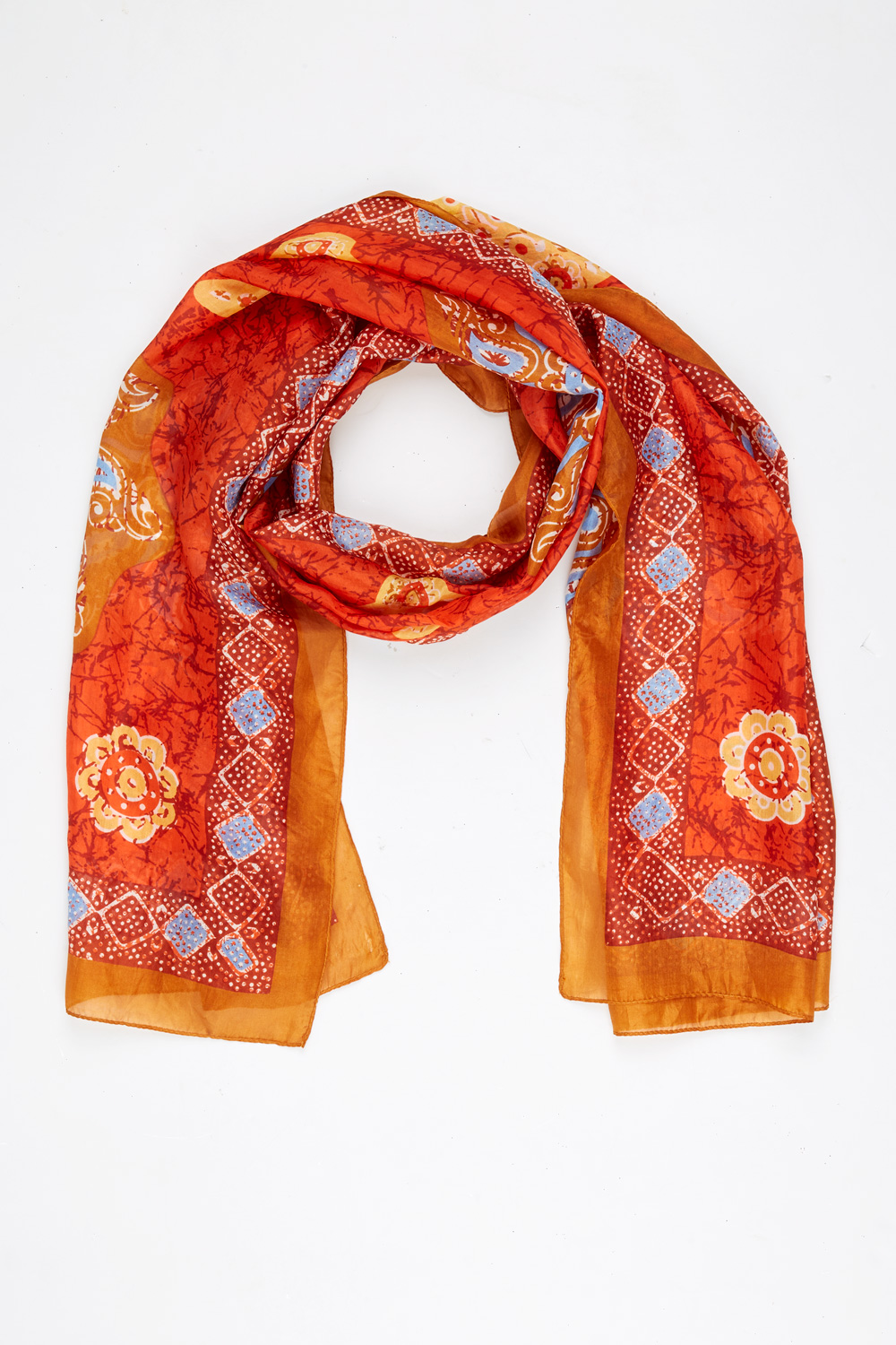 Seidenschal in Rot und Orange mit blauen und gelben floralen und geometrischen Mustern, locker gelegt auf weißem Hintergrund