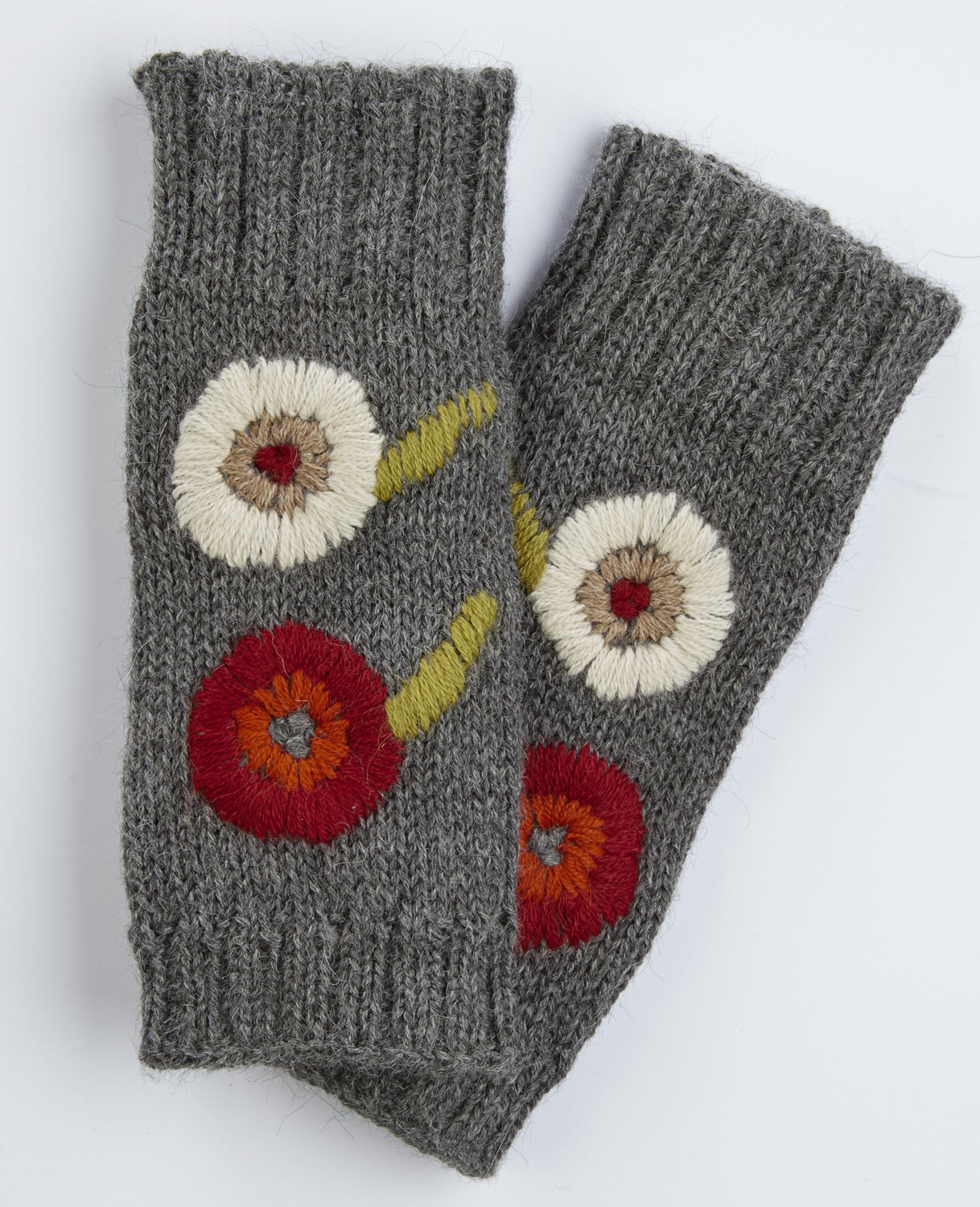 Graue handgestrickte Alpaka-Pulswärmer mit bunten, runden Blumenmustern in Weiß, Rot, Orange und Gelb, weiche wärmende Armstulpen ohne Finger, mit geripptem Bund.