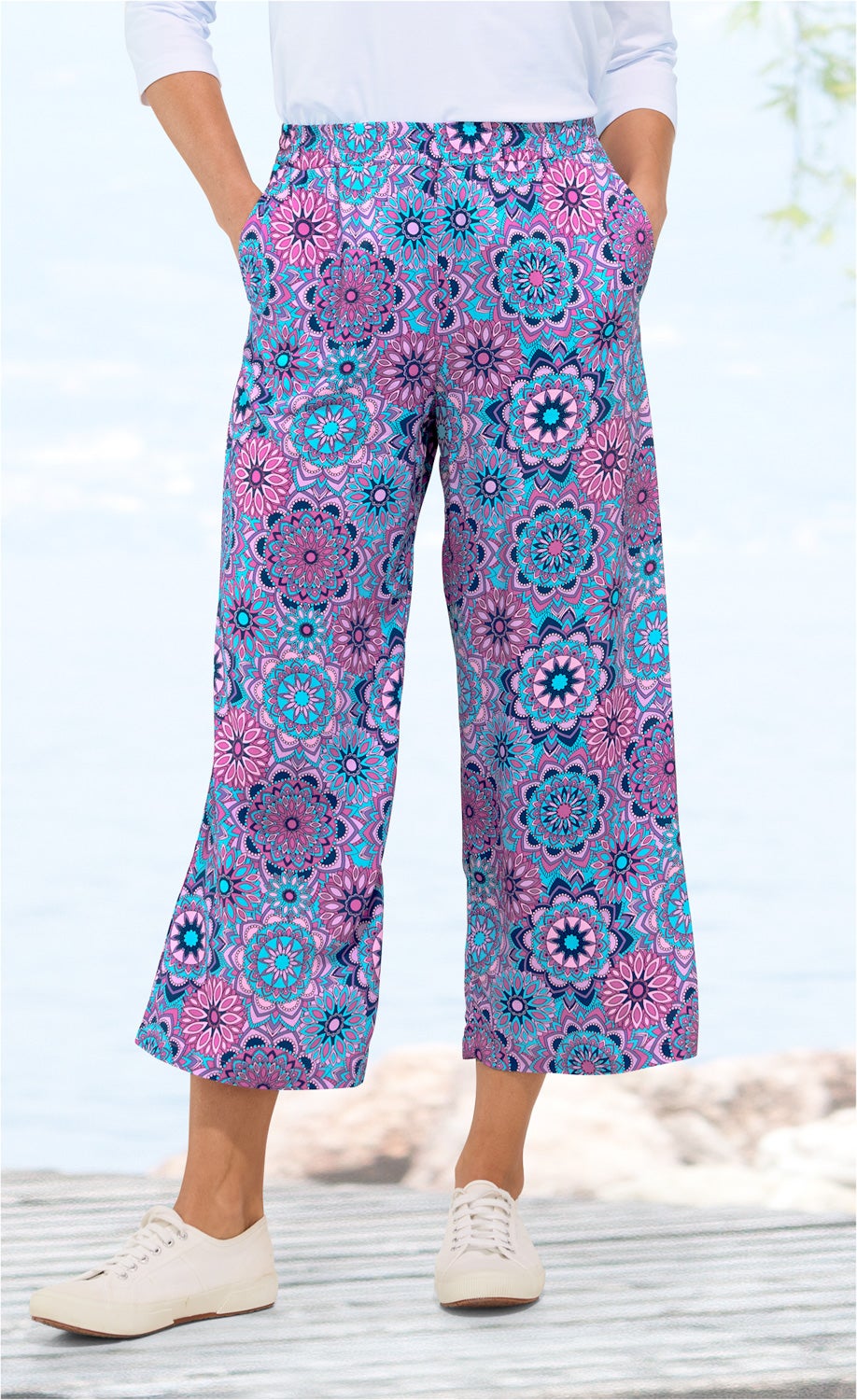 Viskose-Hose mit weitem Bein, buntes Mandala-Blumenmuster in Blau, Pink und Lila, elastischer Bund, seitliche Taschen, getragen mit weißen Sneakern, sommerlicher, lockerer Stil