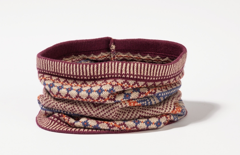Baumwoll-Mix-Schal im Rundschal-Design, mehrfarbig mit geometrischem Muster in Rot-, Blau- und Beigetönen, gestrickt, weicher Stoff, leichte Falten, offener Innenring, flacher Hintergrund weiß