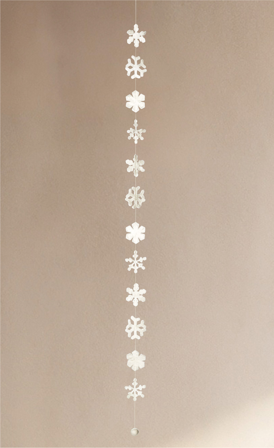 Weiße Girlande 160cm mit verschiedenen Schneeflocken aus Papier, hängend vor beige-kaltem Hintergrund, minimalistisch und winterlich dekorativ.