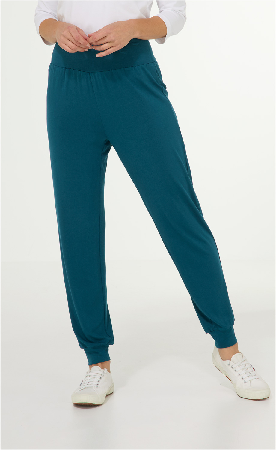 Dunkelblaue Viskose-Mix-Hose mit elastischem Bund und Bündchen am Beinabschluss, lässige Passform, getragen mit weißen Sneakers, Oberkörper teilweise sichtbar mit weißen Ärmeln