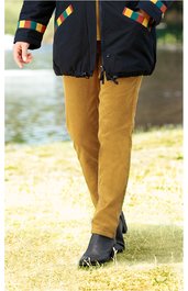 Senfgelbe gerade geschnittene Hose, mittelhoher Bund, getragen von stehender Person, kombiniert mit schwarzer Jacke mit bunten Karomustern an den Taschen, schwarze Stiefeletten