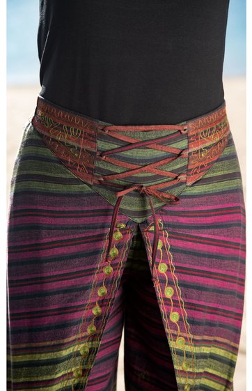 Lange Hose mit weitem Bein, gestreift in Grüntönen, Violett und Dunkelrot, hoher Bund mit Schnürung vorne, Gürtelschlaufen, dekorative gelbe Muster entlang der Naht, getragen von stehender Person