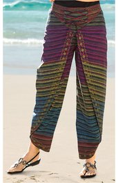 Bunte Hose mit mehrfarbigem Streifenmuster in lila, grün, blau und braun, mit Wickeldetail vorne, locker sitzend, lang, getragen von stehender Person am Strand, mit verstellbarem Bund