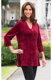 Dunkelrotes Langarmshirt mit V-Ausschnitt, seitlichen Raffungen, kastiger Form, getragen von stehender Frau mit linker Hand auf Hüfte