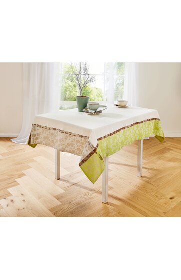 Tischdecke in Creme mit floralem Muster in Beige und Hellgrün, brauner Zierkante, auf rechteckigem Tisch, dekoriert mit grünem Blumentopf, Zweigen und zwei Tassen mit Untertassen