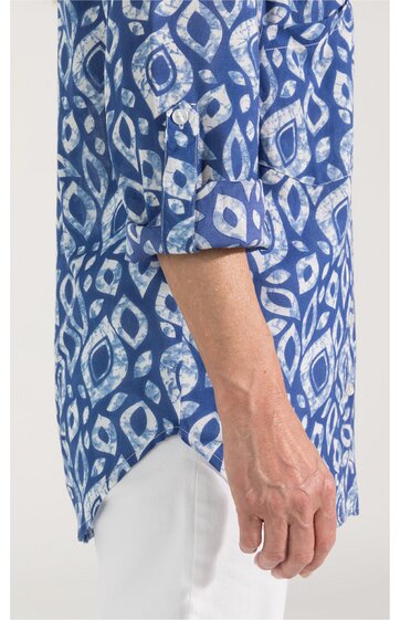 Langärmeliges Hemd in Blautönen mit weißem abstraktem Muster, umgeschlagene Ärmel, abgerundeter Saum mit Seitenschlitzen, getragen von seitlich sichtbarem Oberkörper einer Person
