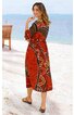 Midikleid in rostrot mit braunem und beigem abstraktem Muster, langärmelig, hoher Ausschnitt, lockere Passform, getragen von stehender Frau am Strand, knielang