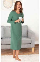 Grünes, langärmliges Kleid, knöchellang, gerade geschnitten, rundhalsausschnitt, getragen von stehender Frau, die eine weiße Tasse hält