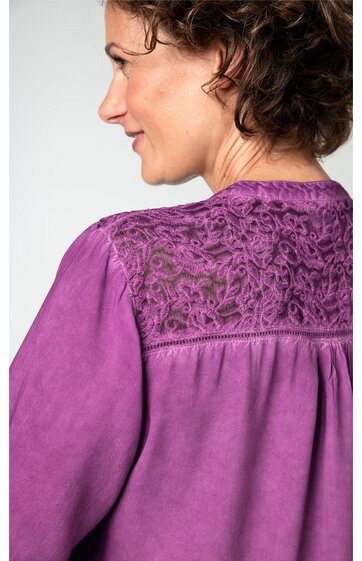 Bluse in violett mit Spitzeneinsatz am Rücken, leichte Falten unterhalb des Spitzeneinsatzes, lange Ärmel, getragen von seitlich stehendem Modell