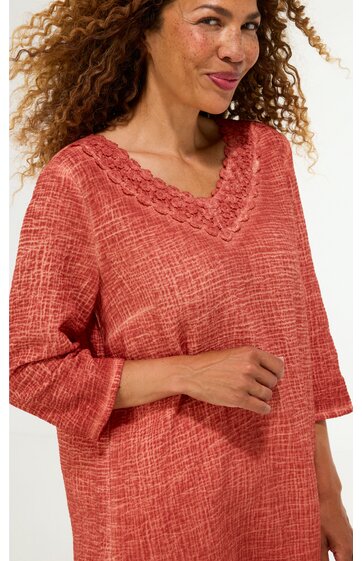 Rotes Strickoberteil mit V-Ausschnitt, strukturierte Maschen, lange Ärmel, getragen von lächelnder stehender Frau, locker geschnitten