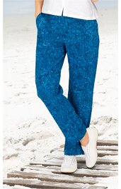 Blaue Stoffhose mit abstraktem Muster, gerader Schnitt, mit Taschen, getragen von stehender Person, kombiniert mit weißen Sneakern