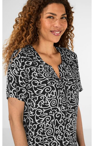 Schwarzes Kurzarmshirt mit weißem abstraktem Muster, V-Ausschnitt mit Knopfleiste, getragen von lächelnder Frau in Dreiviertelansicht