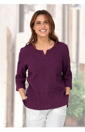 Lila Langarmshirt mit V-förmigem Ausschnitt, strukturierte Oberfläche, lockere Passform, seitliche Taschen, getragen von lächelnder stehender Frau