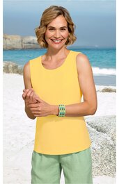 Ärmelloses Top in gelb, rundhalsausschnitt, gerade geschnitten, getragen von lächelnder Frau stehend vor Strandkulisse, kombiniert mit grüner Hose und türkisfarbenem Armband