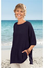 Dunkelblaues, locker geschnittenes Langarmshirt ohne Muster, rundhals, seitliche Taschen, getragen von lächelnder Frau stehend am Strand vor Meer