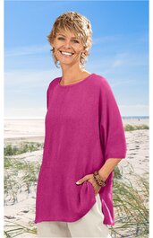 Locker sitzendes, knielanges Damenoberteil in kräftigem Pink, rundhals, halblange Ärmel, Seitenschlitze, getragen von schulterlangen, blonden, lockigen Frau stehend am Strand