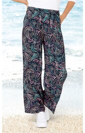 Weite, dunkelblaue Hose mit floralem Muster in Türkis und Violett, elastischer Bund, getragen von Person stehend am Strand, locker fallend