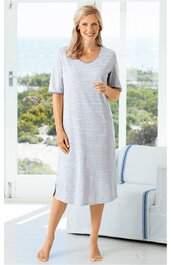 Hellgraues, knielanges Nachthemd mit U-Ausschnitt und kurzen Ärmeln, gerade geschnitten, getragen von stehender Frau vor Fenster, schlichtes Design ohne Muster