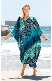 Lockeres Kaftankleid in Türkis und Dunkelblau, Paisley- und abstraktes Muster, V-Ausschnitt, weite Ärmel, knöchellang, getragen von stehender Frau am Strand