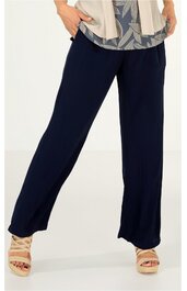 Dunkelblaue gerade geschnittene Hose, weit geschnitten, ohne sichtbare Taschen oder Verzierungen, getragen von stehender Person mit beigefarbenen Sandalen