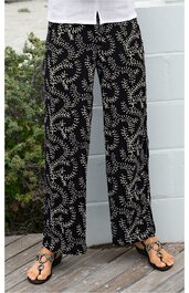 Schwarz-weiße Damenhose mit weißem Blattmuster, gerade geschnitten, knöchellang, elastischer Bund, getragen von stehender Person mit Sandalen