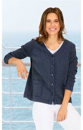 Dunkelblaue locker geschnittene Strickjacke mit Knöpfen, V-Ausschnitt, zwei großen Taschen vorne, getragen von stehender Frau mit weißem T-Shirt und weißer Hose vor Meereshintergrund
