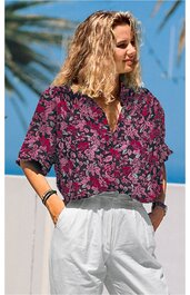 Kurzärmlige Bluse in dunklem Magenta mit floralem Muster in Grau und Schwarz, V-Ausschnitt, lockere Passform, getragen von stehender Person, weißer Bundhose mit elastischem Taillenbund