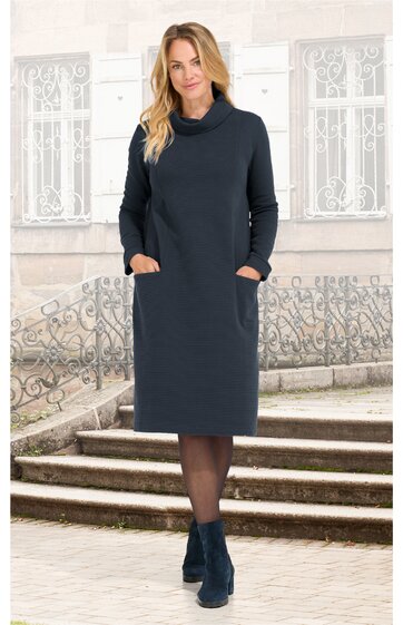 Dunkelblaues, knielanges Kleid mit Rollkragen, langärmelig, seitliche Eingrifftaschen, getragen von stehender Frau, gerade geschnitten