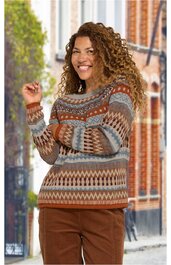 Pullover in Braun- und Blautönen mit geometrischem Muster, Rundhalskragen, lange Ärmel, getragen von stehender Frau mit erhobenem Arm, kombiniert mit brauner Hose