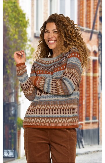 Pullover in Braun- und Blautönen mit geometrischem Muster, Rundhalskragen, lange Ärmel, getragen von stehender Frau mit erhobenem Arm, kombiniert mit brauner Hose