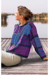 Pullover mit Kapuze in Violett und Blau, geometrisches Muster in Schwarz, langärmlig, vorne mit Kordelzug, locker geschnitten, getragen von sitzender Person seitlich gewandt auf Holzsteg am Wasser