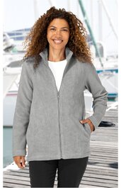 Hellgraue Fleecejacke, einfarbig, durchgehender Reißverschluss, Stehkragen, Seitentaschen, lange Ärmel, gerade geschnitten, getragen von stehender Frau vor maritimem Hintergrund