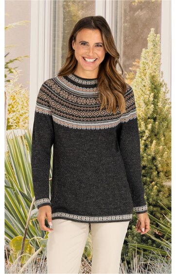 Dunkelgrauer Pullover mit Norwegermuster in Hellgrau und Beige am oberen Teil und an den Bündchen, Rundhals, langärmelig, gerade geschnitten, getragen von stehender Frau