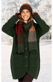 Dunkelgrüner Mantel mit großen Taschen, Knopfleiste, knielang, getragen von stehender lächelnder Frau mit brauner Mütze, dunkelrotem Schal mit orange und grauen Querstreifen, braune Handschuhe, Winterlandschaft im Hintergrund