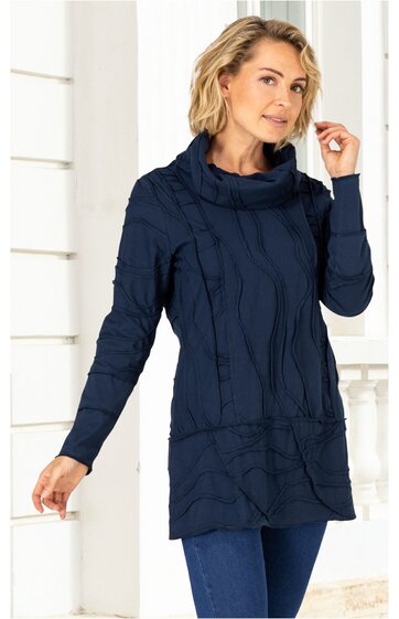 Marineblauer Pullover mit Zopfmuster, langer Schnitt mit Seitentaschen, hoher Rollkragen, lange Ärmel, getragen von stehender Frau mit blonden, schulterlangen Haaren