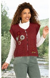 Rotes Strickweste mit Blumendekor auf der Vorderseite, Knopfleiste, rundem Ausschnitt, ohne Ärmel, getragen von lächelnder stehender Frau mit weißem Rollkragenpulli und grüner Hose