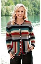 Gestrickte Jacke in Rot, Dunkelgrün, Grau und Beige, mehrfarbig gestreift, Rundhalsausschnitt, Knopfleiste mit weißen Knöpfen, lange Ärmel, mit Taschen, getragen von lächelnder Frau vor Wasser und Bäumen