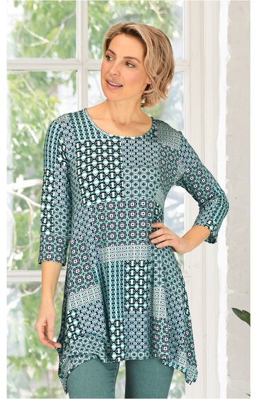 Tunika zur Damenbekleidung in Petrol und Blau, Patchwork-Muster aus geometrischen Formen, Rundhalsausschnitt, 3/4-Ärmel, locker fallend, von stehender Frau getragen