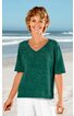 Damenpullover in dunklem Tannengrün, unifarben, V-Ausschnitt, kurze Ärmel, gerade geschnittener Saum mit kleinen seitlichen Schlitzen, getragen von lächelnder, stehender Frau am Strand