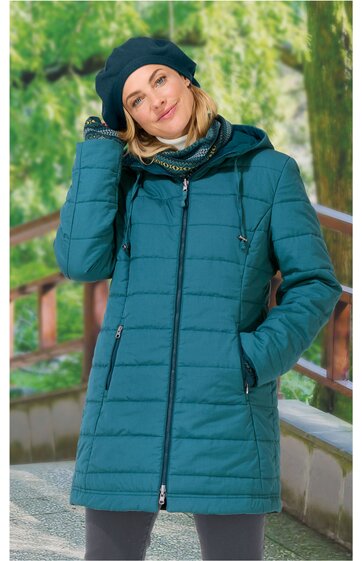 Dunkeltürkise Steppjacke mit durchgehendem Reißverschluss, zwei seitlichen Reißverschlusstaschen, hohem Kragen, Kapuze, gerade geschnitten, getragen von stehender Frau mit blonder schulterlanger Haaren, die mit linker Hand ihre Mütze berührt