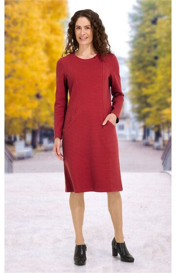 Rotes, knielanges Kleid mit rundem Ausschnitt, langen Ärmeln, aufgesetzten Taschen an den Seiten, gerade geschnitten, getragen von stehender Frau mit offenen Haaren, schwarze Stiefeletten