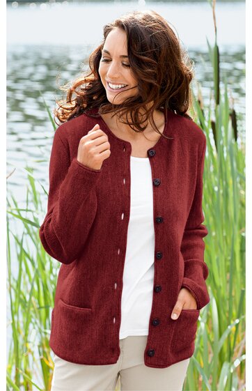 Bordeauxrote Strickjacke mit durchgehender Knopfleiste, Rundhalsausschnitt, lange Ärmel, zwei seitliche Eingrifftaschen, getragen von lächelnder stehendem Frau vor natürlichem Hintergrund