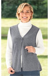 Graue ärmellose Strickweste mit V-Ausschnitt und durchgehendem Reißverschluss vorne, getragen von lächelnder Frau im Stehen, darunter weißer Rollkragenpullover, gerade geschnitten