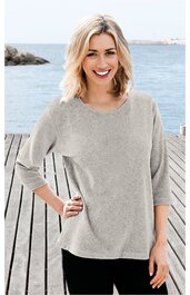 Hellgraues Langarmshirt ohne Muster, rundhalsig, locker geschnitten, mit 3/4-Ärmeln, getragen von lächelnder Frau mit blondem, schulterlangem Haar, stehend an Holzsteg am Wasser